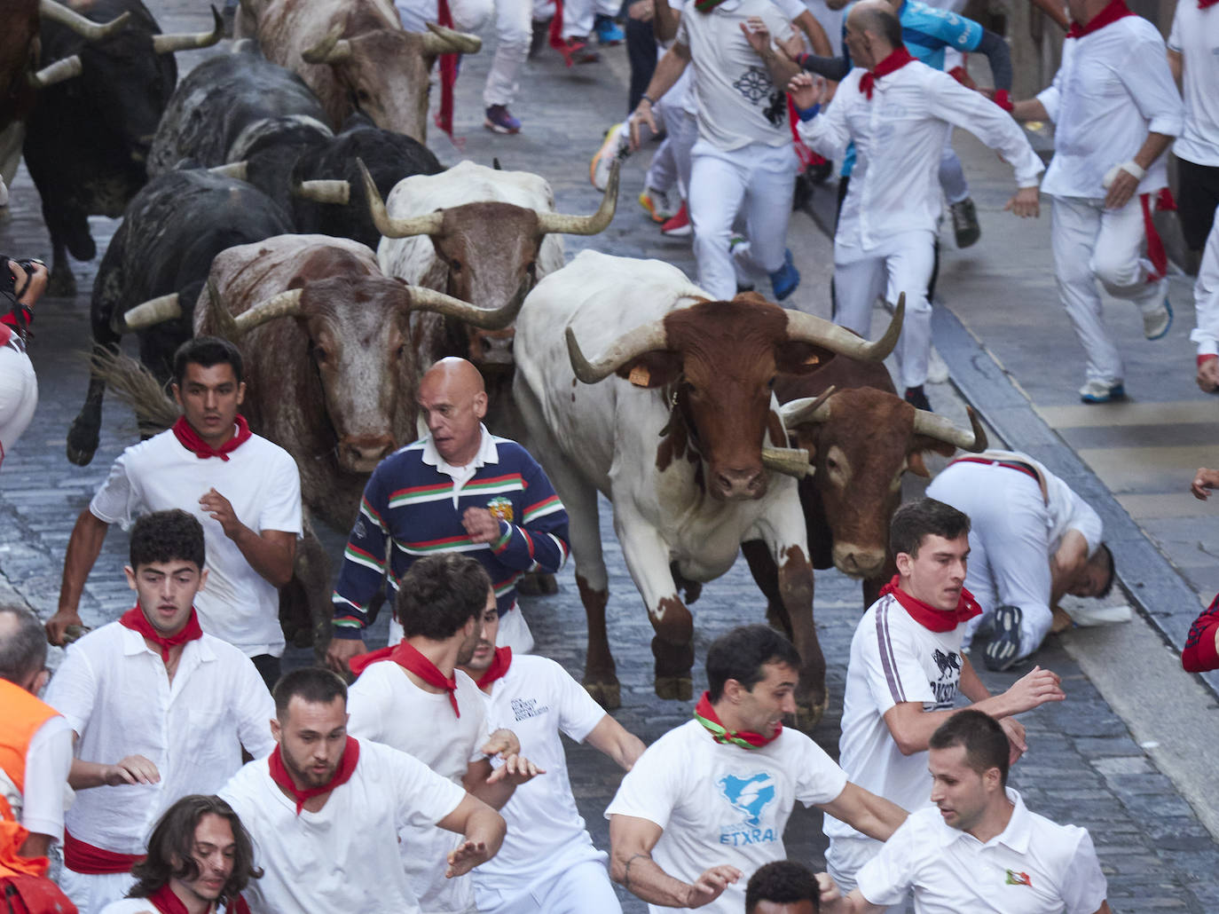 Varias personas corren frente a los toros de la ganadería abulense de José Escolar durante el tercer encierro de las Fiestas de San Fermín 2023, el 9 de julio, en Pamplona, Navarra