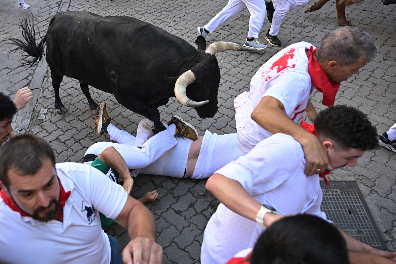 Un mozo caído, durante del séptimo encierro de los sanfermines con toros de la ganadería de Victoriano del Río