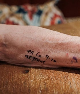 Imagen secundaria 2 - Arriba, Antonio López, portando el lienzo en blanco hasta el centro de la Puerta del Sol, acompañado por su amigo y pintor Isidro Brunete, que lleva los bártulos. Sobre estas líneas, a la izquierda, el pintor midiendo meticulosamente antes de coger el pincel. A la derecha, detalle de su antebrazo izquierdo, donde lleva escrito el lugar exacto desde el que pinta: en la losa 9-10 