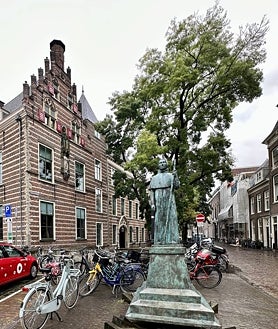 Imagen secundaria 2 - Arriba, la estación de la ciudad, al anochecer. Abajo, un detalle de la casa del Papa Adriano y la estatua del mismo Papa en la ciudad