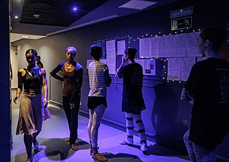 Imagen secundaria 1 - Mientras que el equipo técnico moviliza todos los tutús de los cisnes con perchas móviles, las bailarinas comprueban el elenco que cada día se imprime y se pone en las bambalinas del Teatro Real