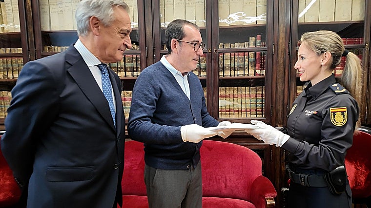 La investigadora de la Brigada de Patrimonio Histórico Ruth García entrega los documentos a Juan José Alonso, director del Archivo General de Palacio, en presencia del comisario Jesús Ignacio Martín