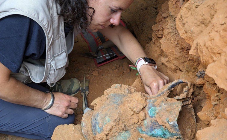 Imagen principal - Miembros del equipo de 'Construyendo Tarteso' desentierran una jarra de bronce, una vasija cerámica y uno de los fragmentos de la columna