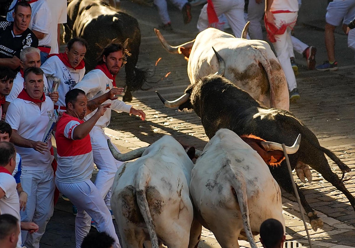 Los mozos son perseguidos por toros de la ganadería Victoriano del Río Cortés durante el cuarto encierro de los Sanfermines