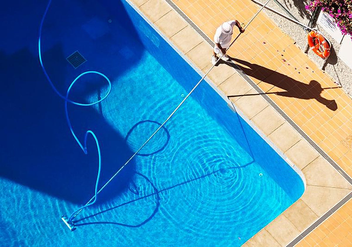 Un socorrista limpiando una piscina comunitaria