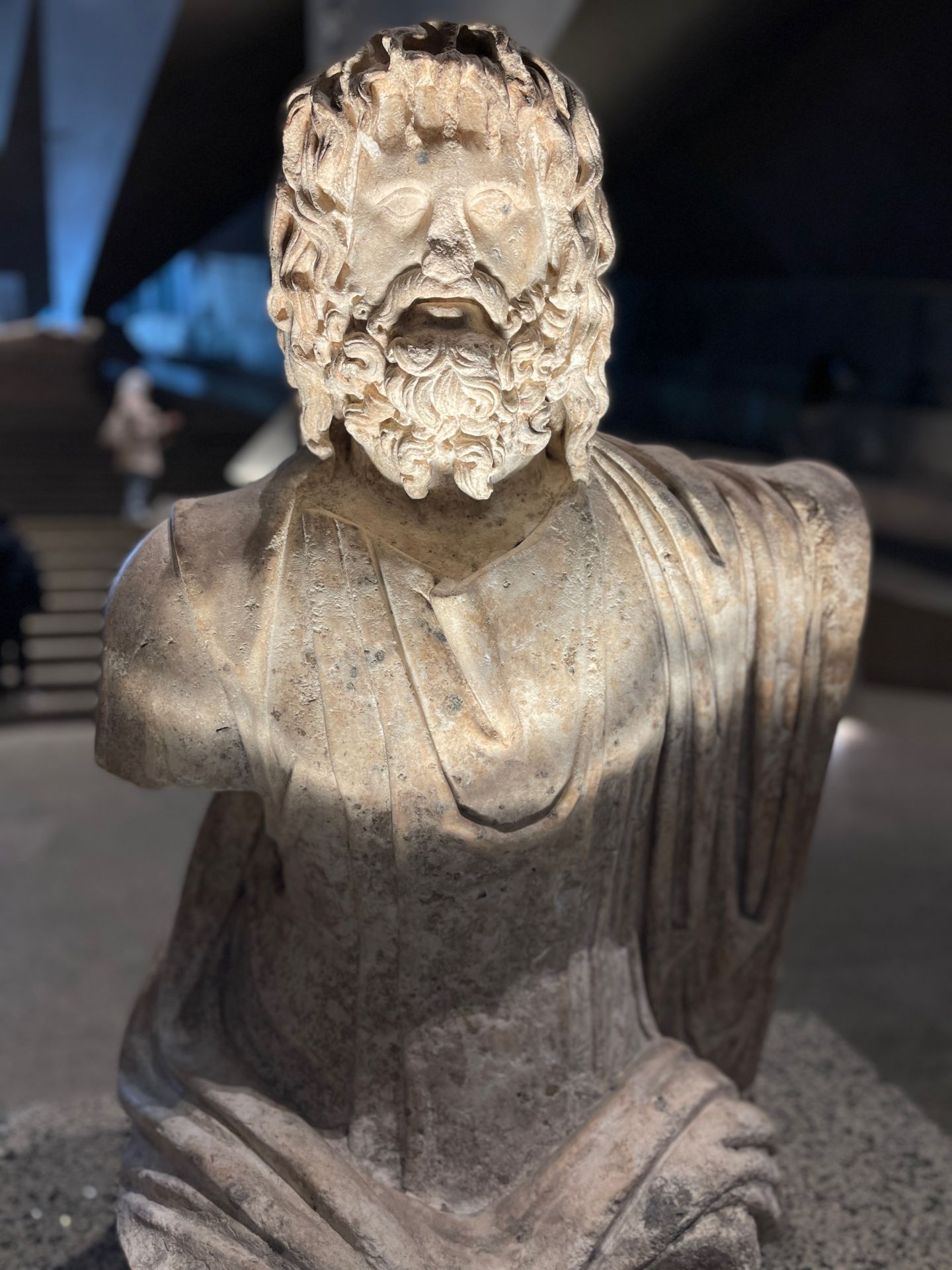 También el dios Serapis, cuyo culto se extendió desde Alejandría, la capital ptolemaica, tiene su sitio en la escalinata del GEM. Serapis representaba el inframundo, la fertilidad y las cosechas, así como cualidades divinas de los reyes, según recuerdan en la cartela de esta escultura del periodo grecorromano