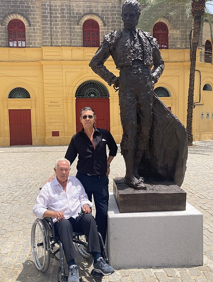 Curro Romero posa con Jesús Soto de Paula ante la escultura de Rafael de Paula delante de la plaza de toros de Jerez