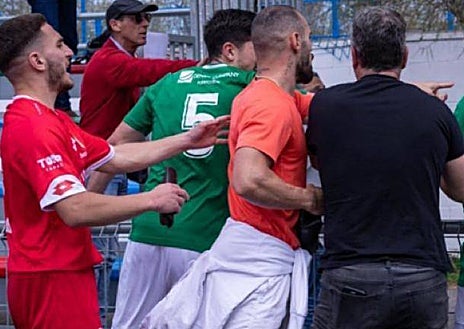 Imagen secundaria 1 - Adrián P (de naranja), jugador del Puerto Real, no pudo jugar el partido al estar sancionado, pero presenció el encuentro junto al banquillo de su equipo e intervino en la tangana tras el pitido final, en la que varios rivales fueron agredidos. 