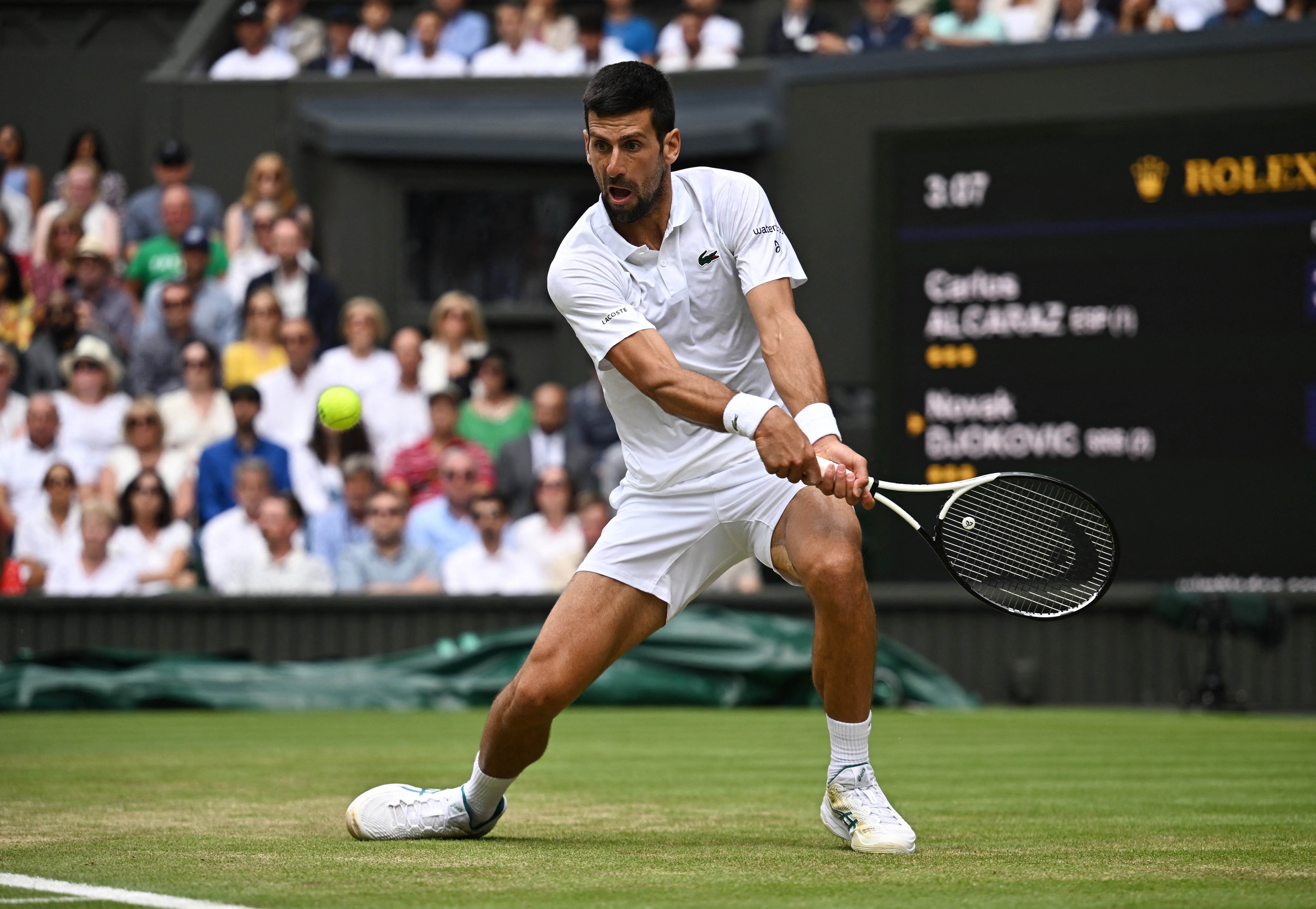 El serbio Novak Djokovic le devuelve el balón al español Carlos Alcaraz durante el último partido de tenis individual masculino en el último día del Campeonato de Wimbledon 2023