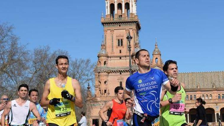 Varios corredores pasan por la plaza de España del parque de María Luisa durante el Zurich Maratón Sevilla 2023