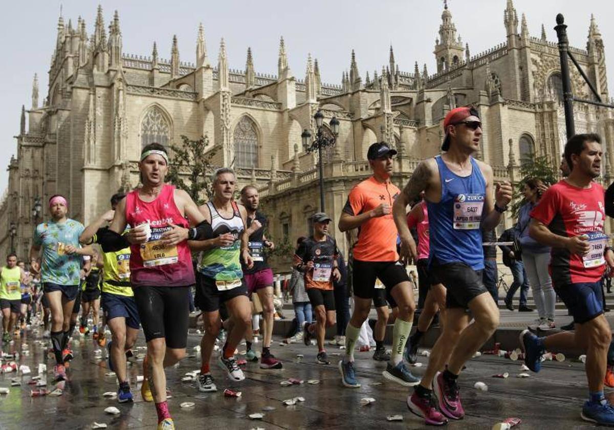 Varios corredores pasan por la Catedral de Sevilla en el Zurich Maratón 2023