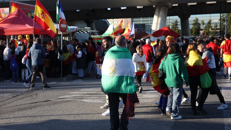 Un seguidor porta la bandera de Andalucía en los aledaños del estadio de la Cartuja, entre una nube de camisetas rojas