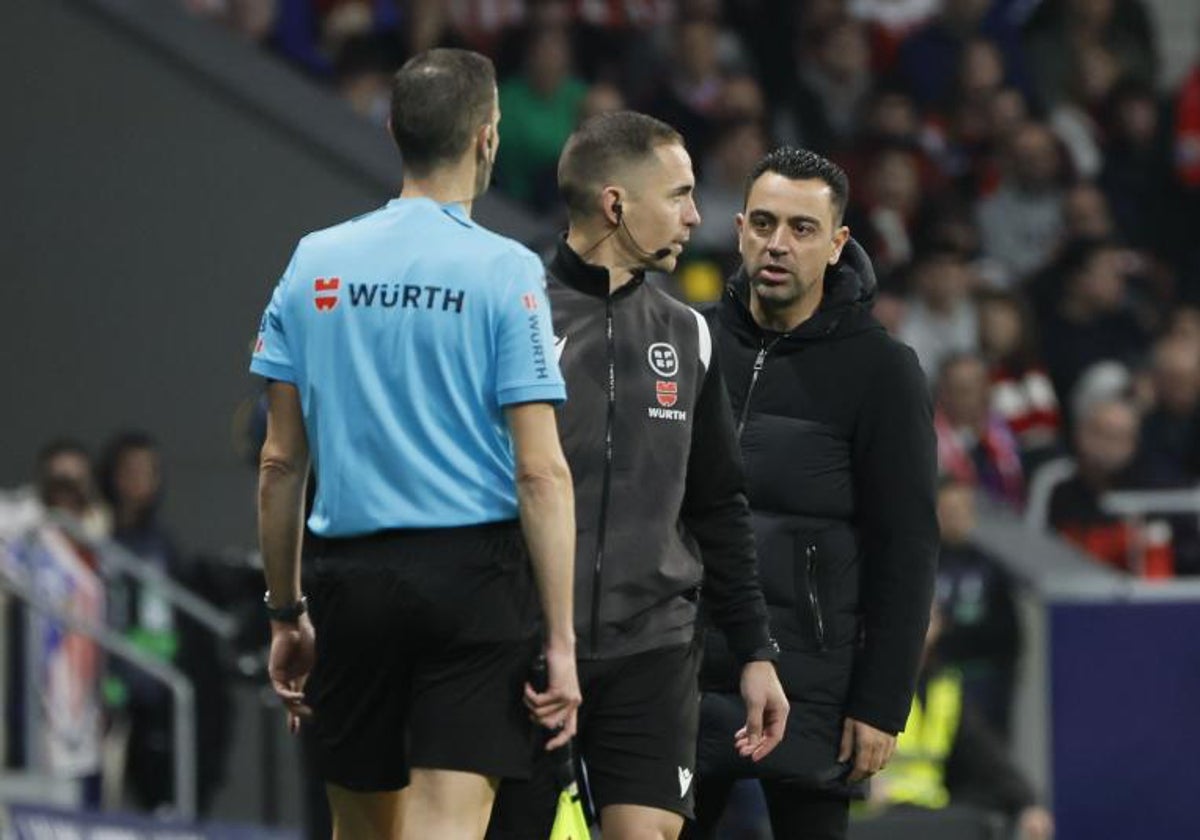 Xavi, con el árbitro y el cuarto árbitro del Atlético-Barcelona