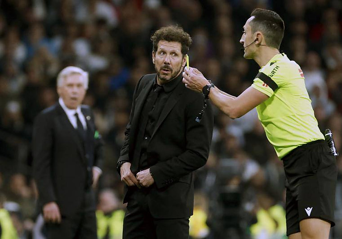 El colegiado Sánchez Martínez conversa con el entrenador del Atlético, Diego Pablo Simeone, en el derbi madrileño de la temporada 2023-24