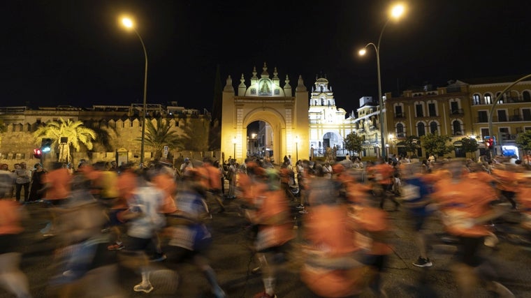 La Carrera Nocturna de 2023, pasando por delante del Arco y la Basílica de la Macarena