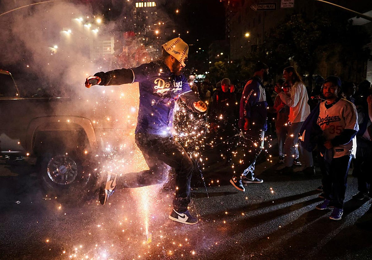 Un aficionado salta entre fuegos artificiales durante la celebración del título de los Dodgers