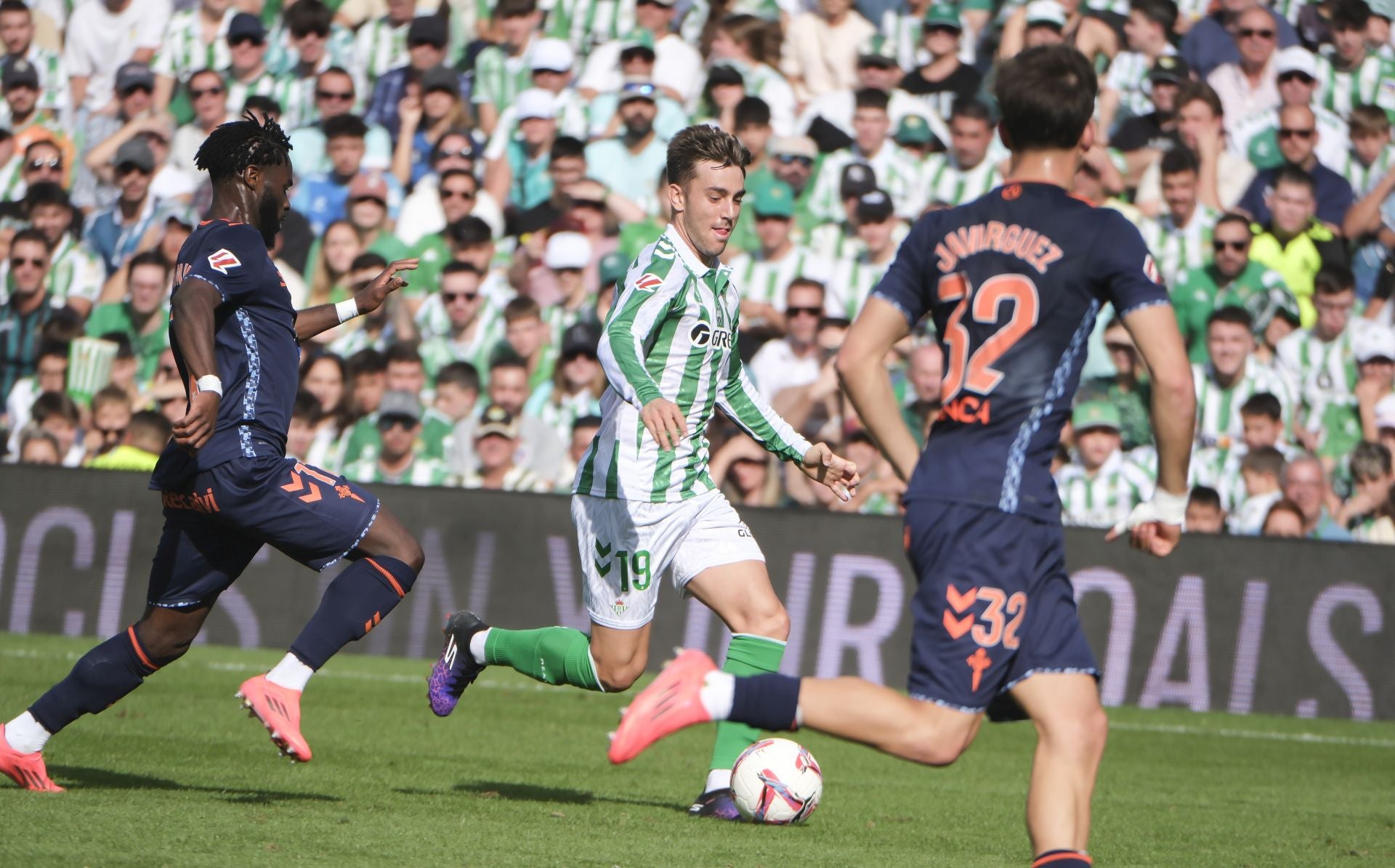 Losada avanza ante Bamba y Javi Rodríguez durante el Betis - Celta en el Benito Villamarín