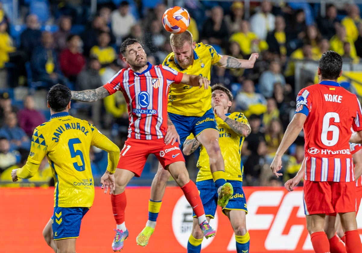 El delantero de Las Palmas Oliver McBurnie salta por el balón con el lateral del Atlético Javi Galán
