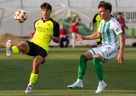 Carlos Reina, del filial verdiblanco, intenta controlar el balón ante un jugador del Antequera