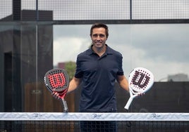 Fernando Belasteguín posando en la red del Bela Padel Center con sus palas