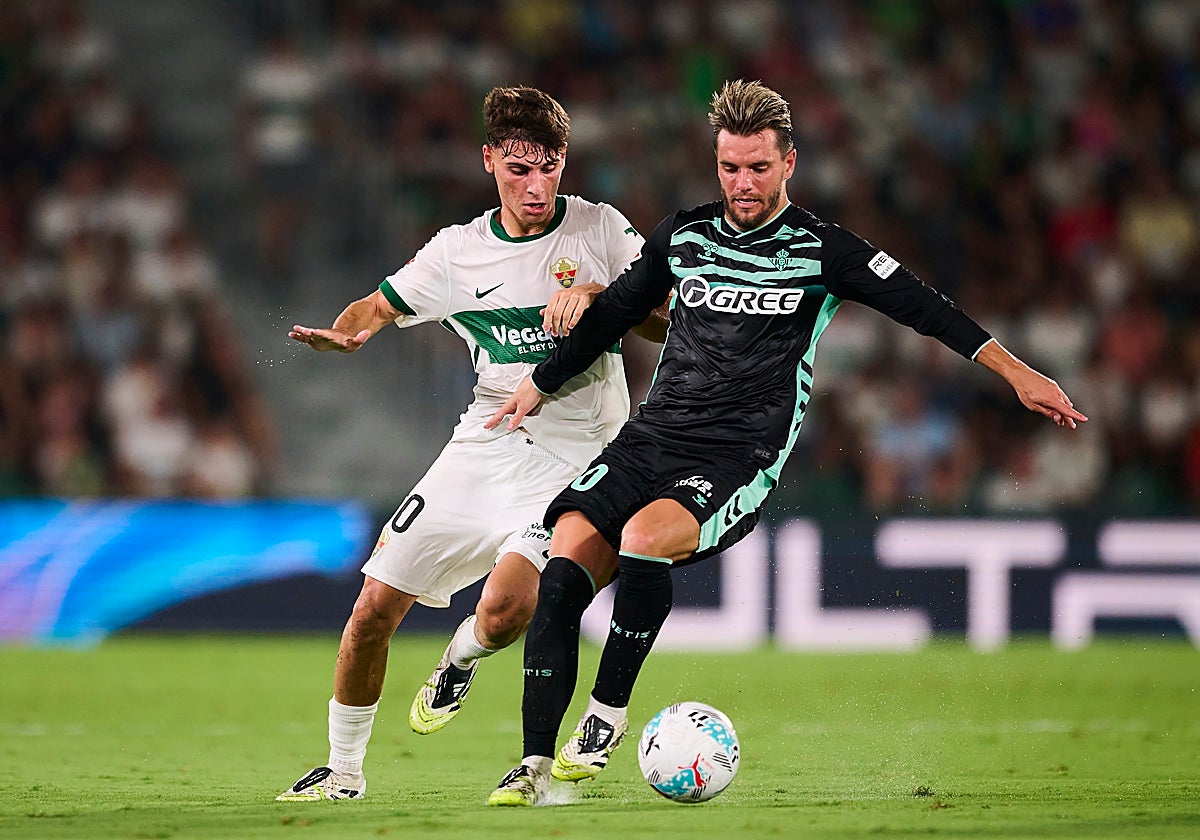 Lo Celso protege la pelota ante la presión de Mendoza, jugador del Elche