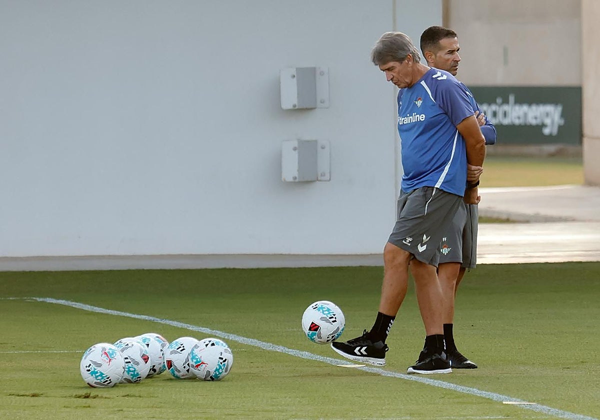 Manuel Pellegrini toca un balón ante Fernando durante el entrenamiento del Betis en la ciudad deportiva Luis del Sol