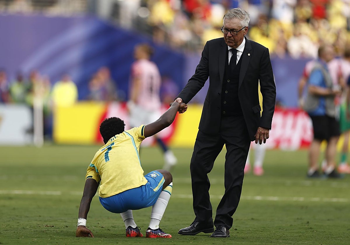Ancelotti ayuda a Vinicius a levantarse del césped tras la derrota ante Noruega.