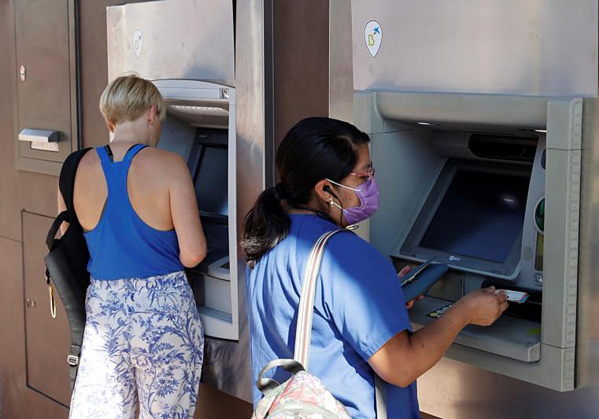 Dos personas en los cajeros de una entidad bancaria en Madrid