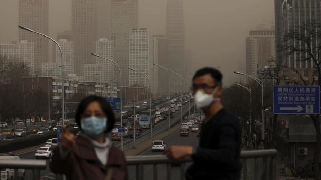 Un hombre y una mujer se protegen con máscaras de la nube de contaminación que cubre la ciudad de Pekín