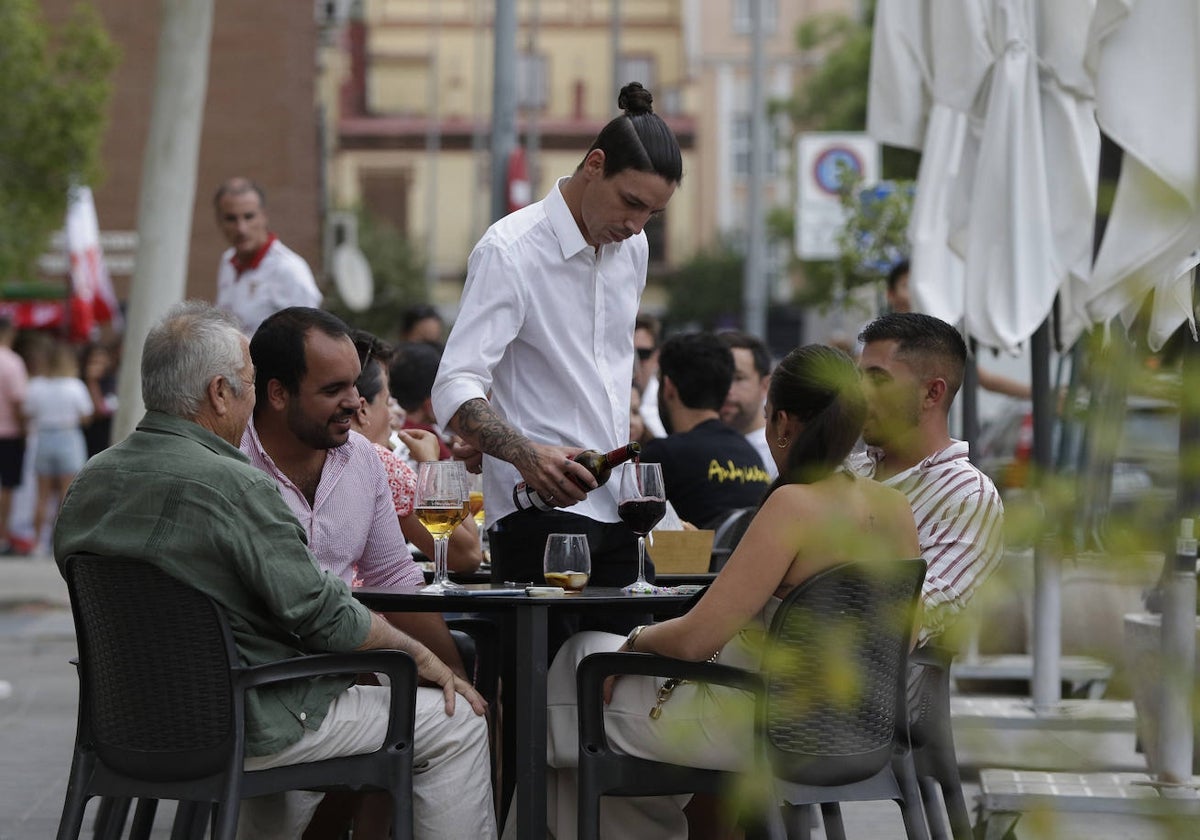 Un camarero sirve en la terraza de un bar en Sevilla