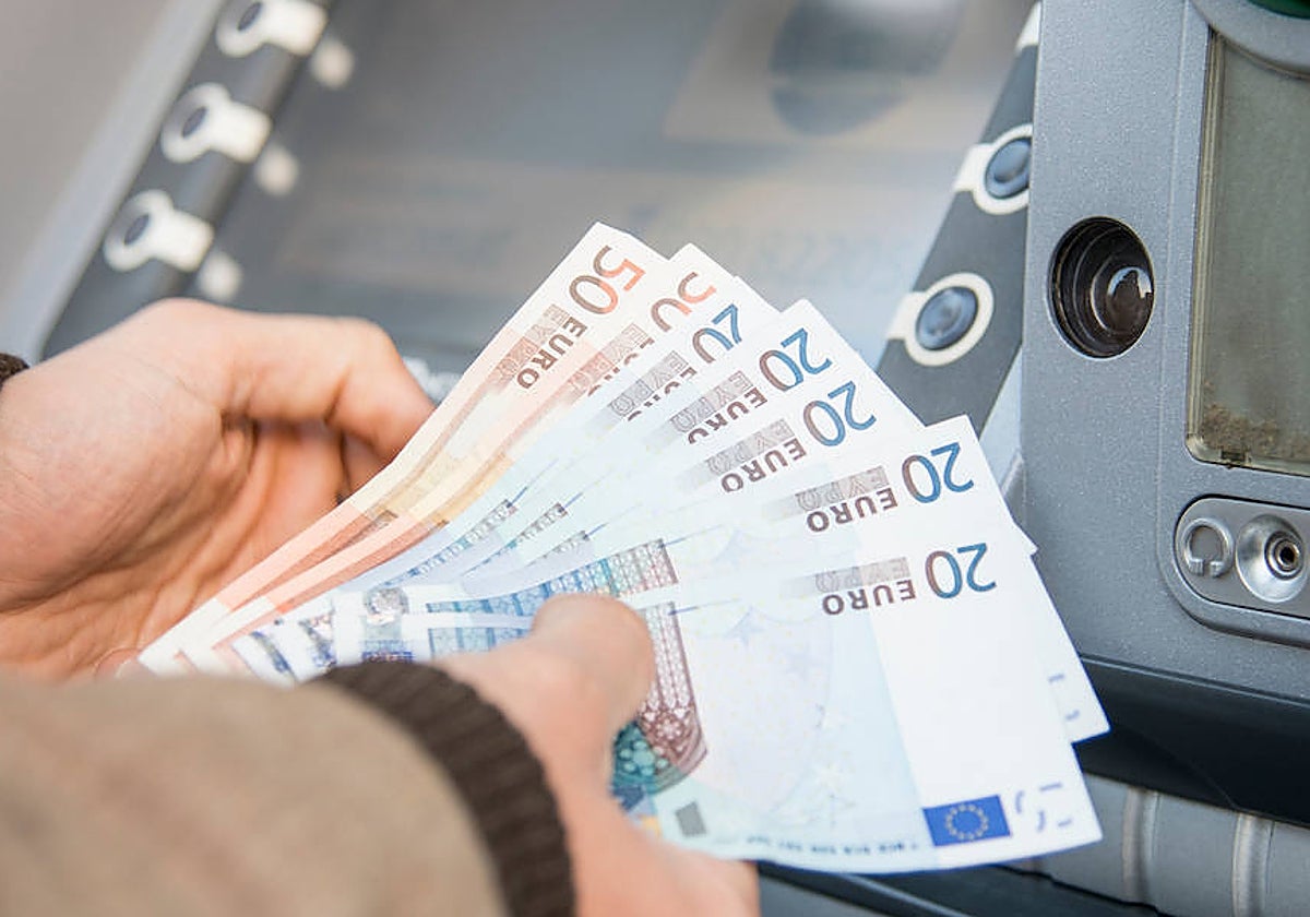 Un usuario retira dinero en efectivo de la sucursal bancaria