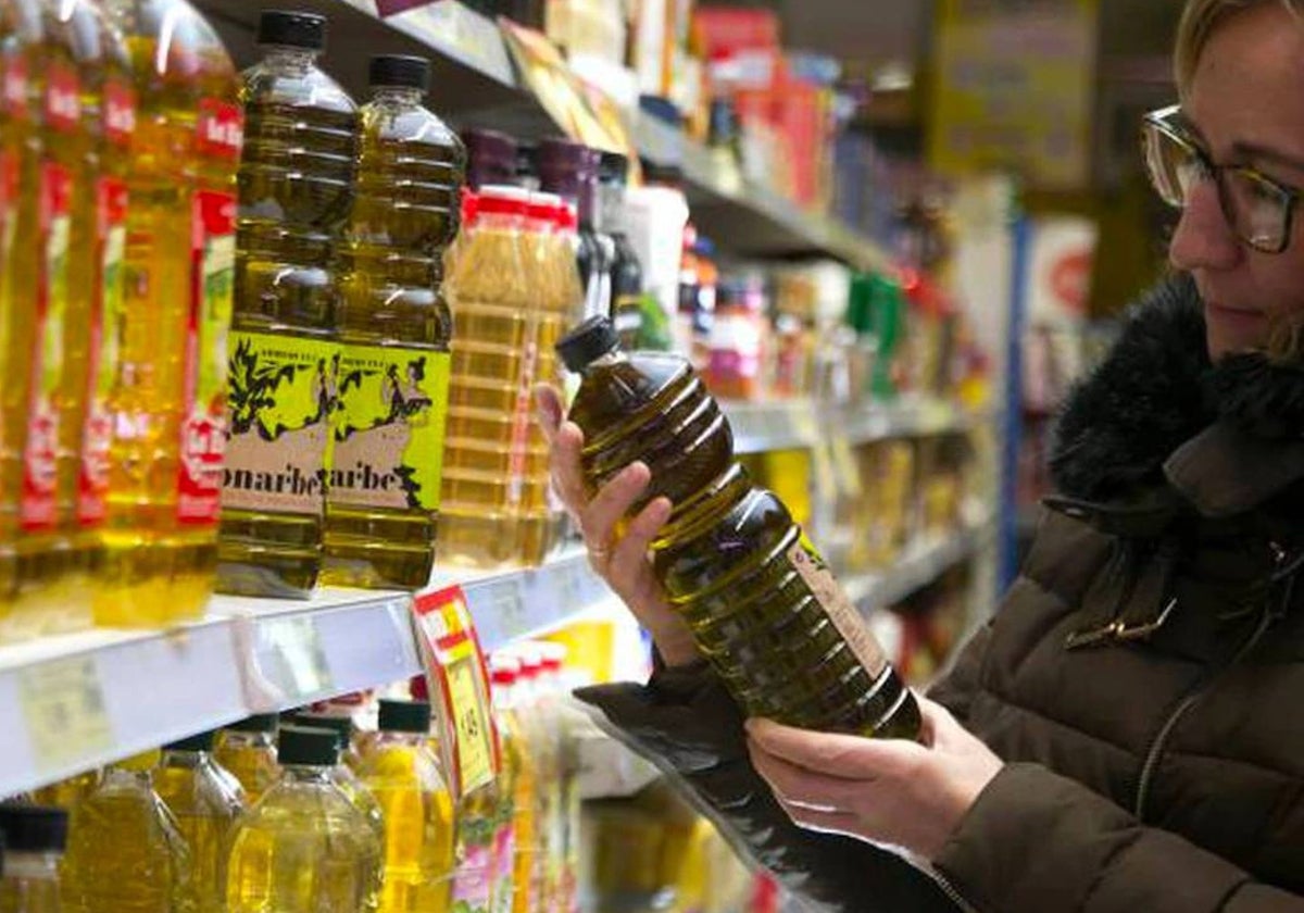 Una mujer observa una botella de aceite en el supermercado