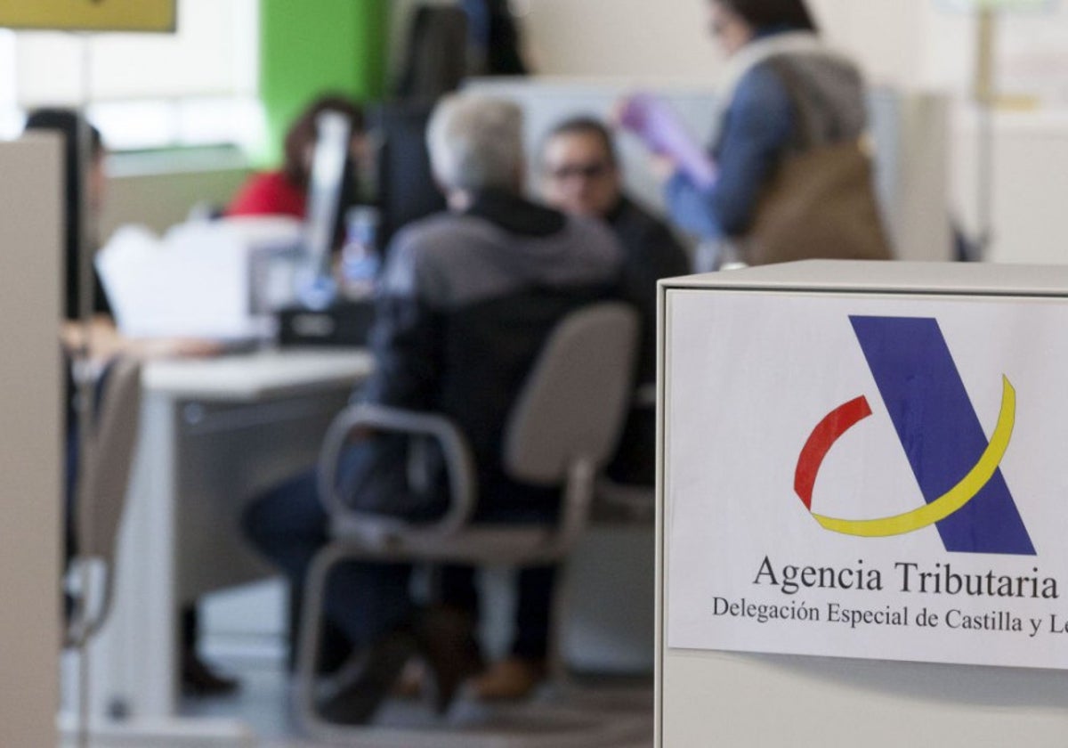 Un funcionario atiende a unos contribuyentes en una oficina de Hacienda en Castilla y León