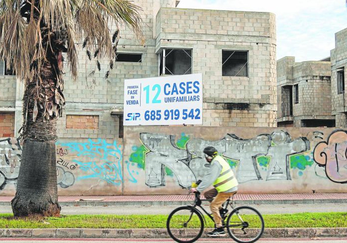 Un hombre en bicicleta frente a varias viviendas en construcción, en Menorca