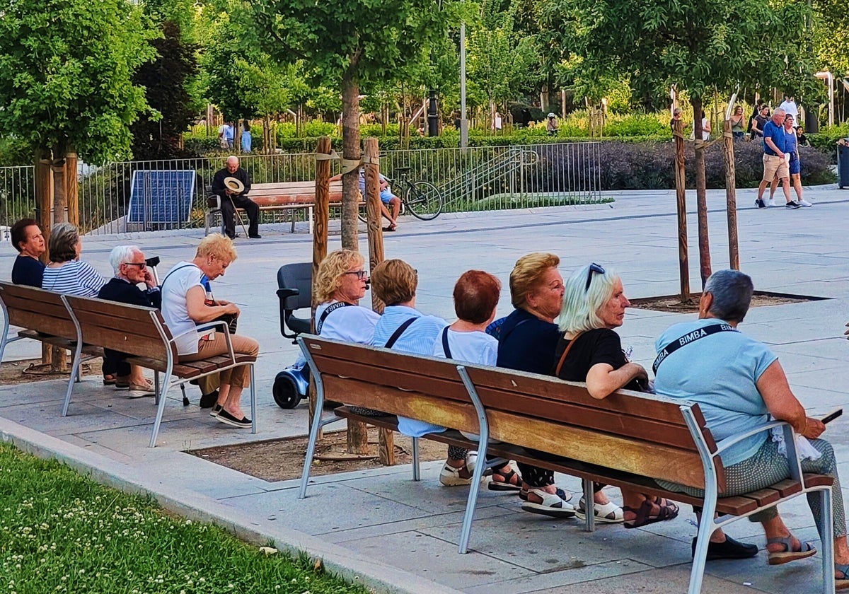 Un grupo de personas sentadas en los bancos de la Plaza de España (Madrid)