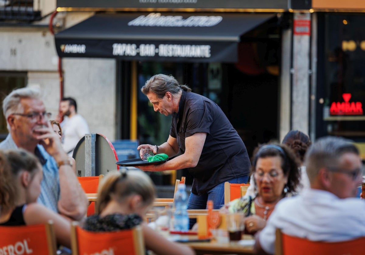 Un camarero atiende a clientes en una terraza de Madrid