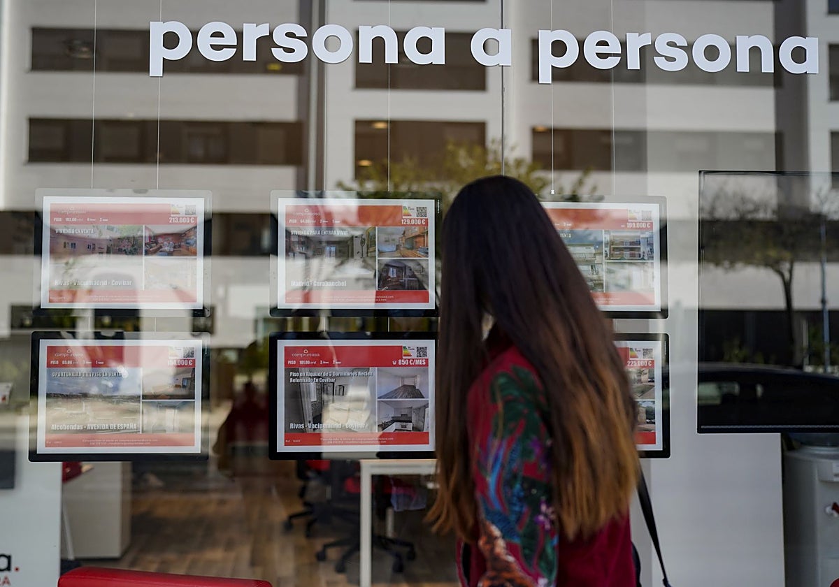 Una joven frente al escaparate de una inmobiliaria