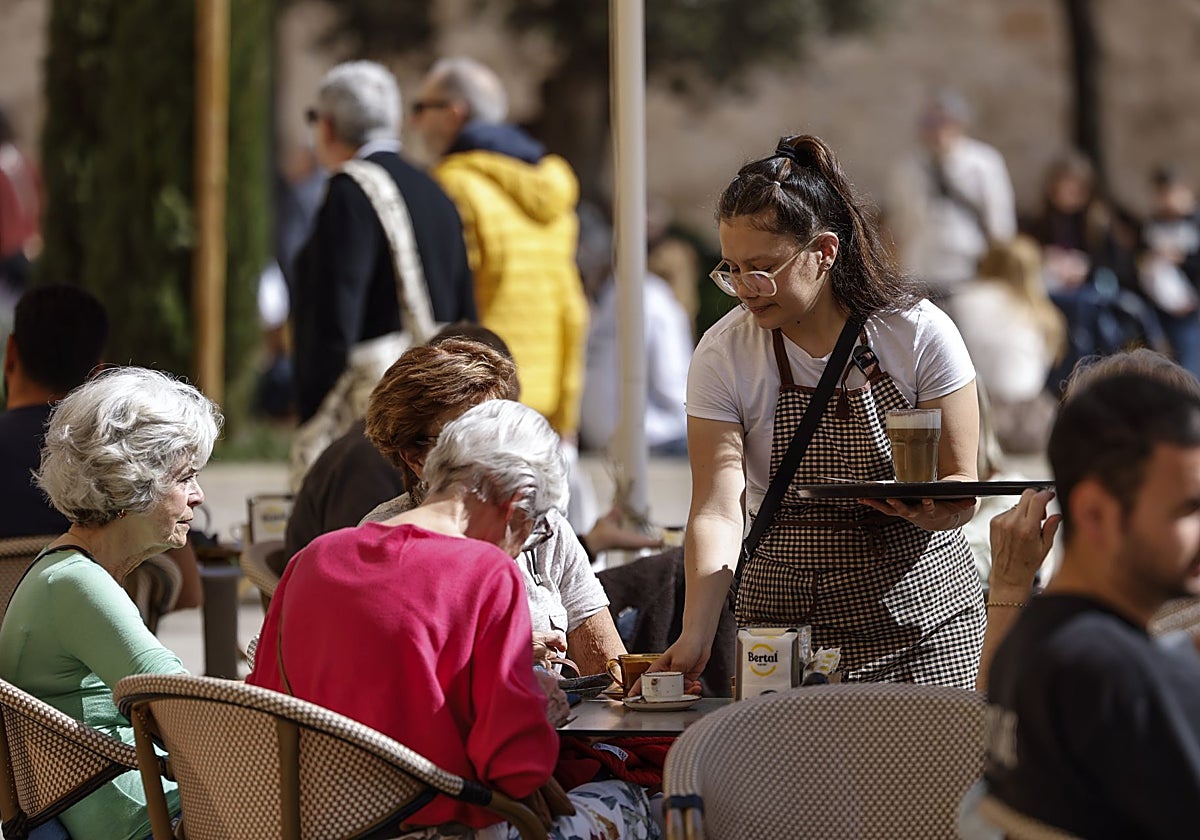 Una camarera atiende una mesa en una terraza en la ciudad de Valencia