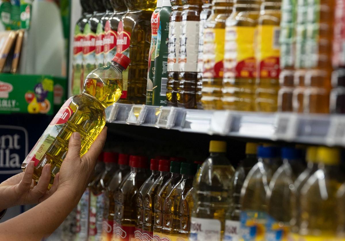 Una persona coge una botella de aceite en un supermercado español