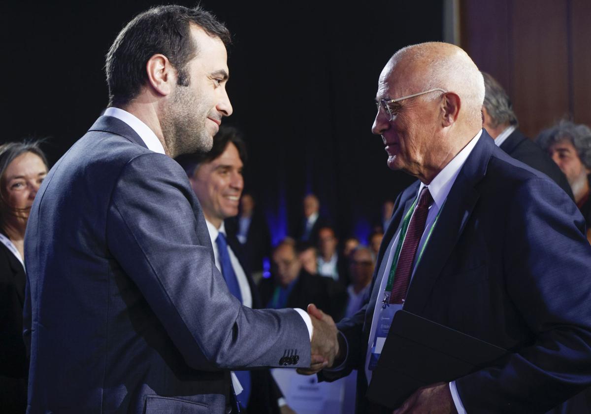 El ministro de Economía, Carlos Cuerpo, saluda al presidente del Banco Sabadell, Josep Oliu.