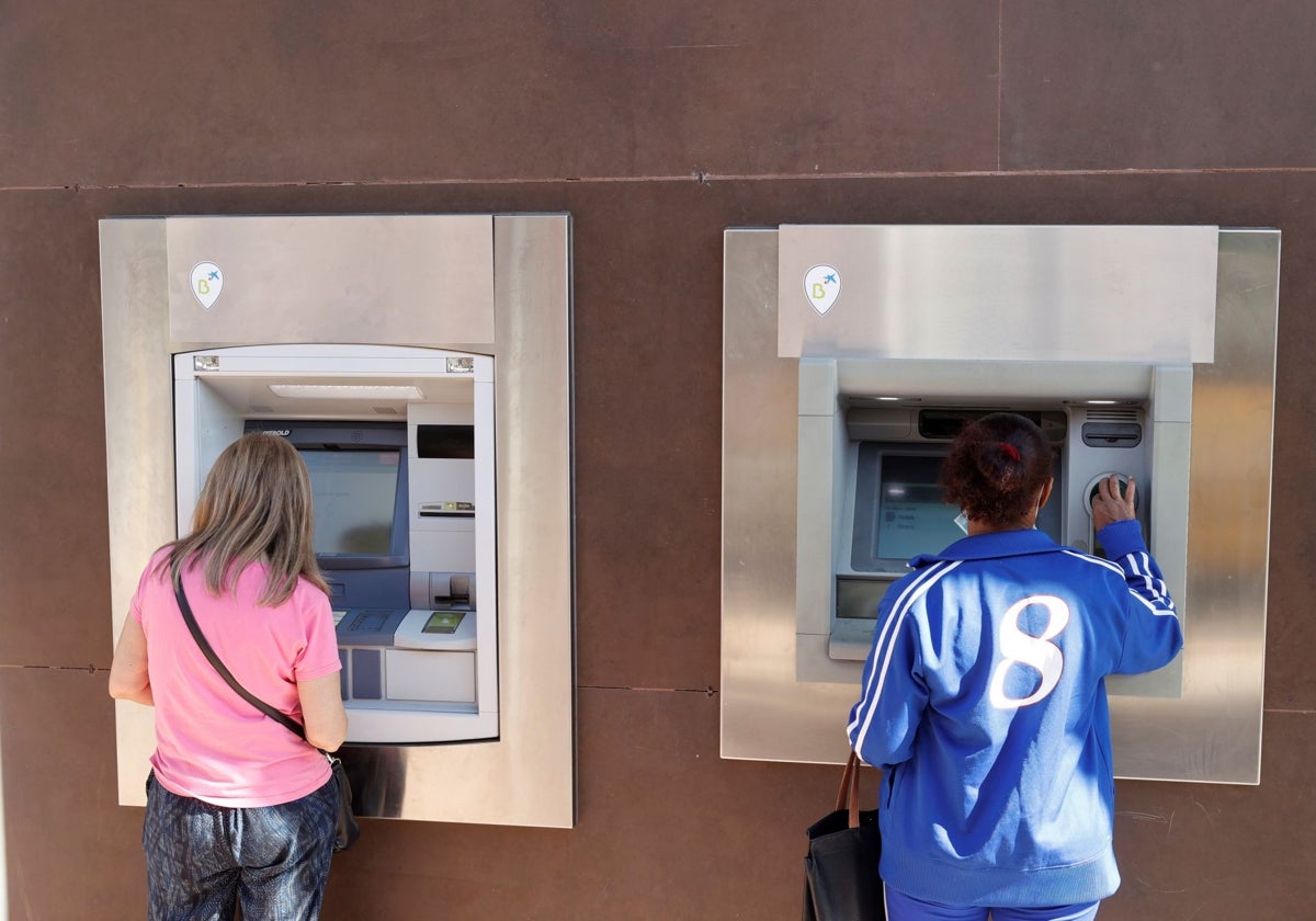 Dos mujeres sacan dinero de cajeros automáticos