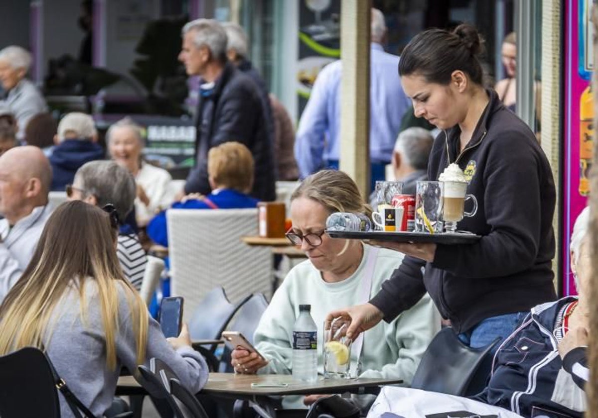 Una camarera atiende a unos turistas en Benidorm.
