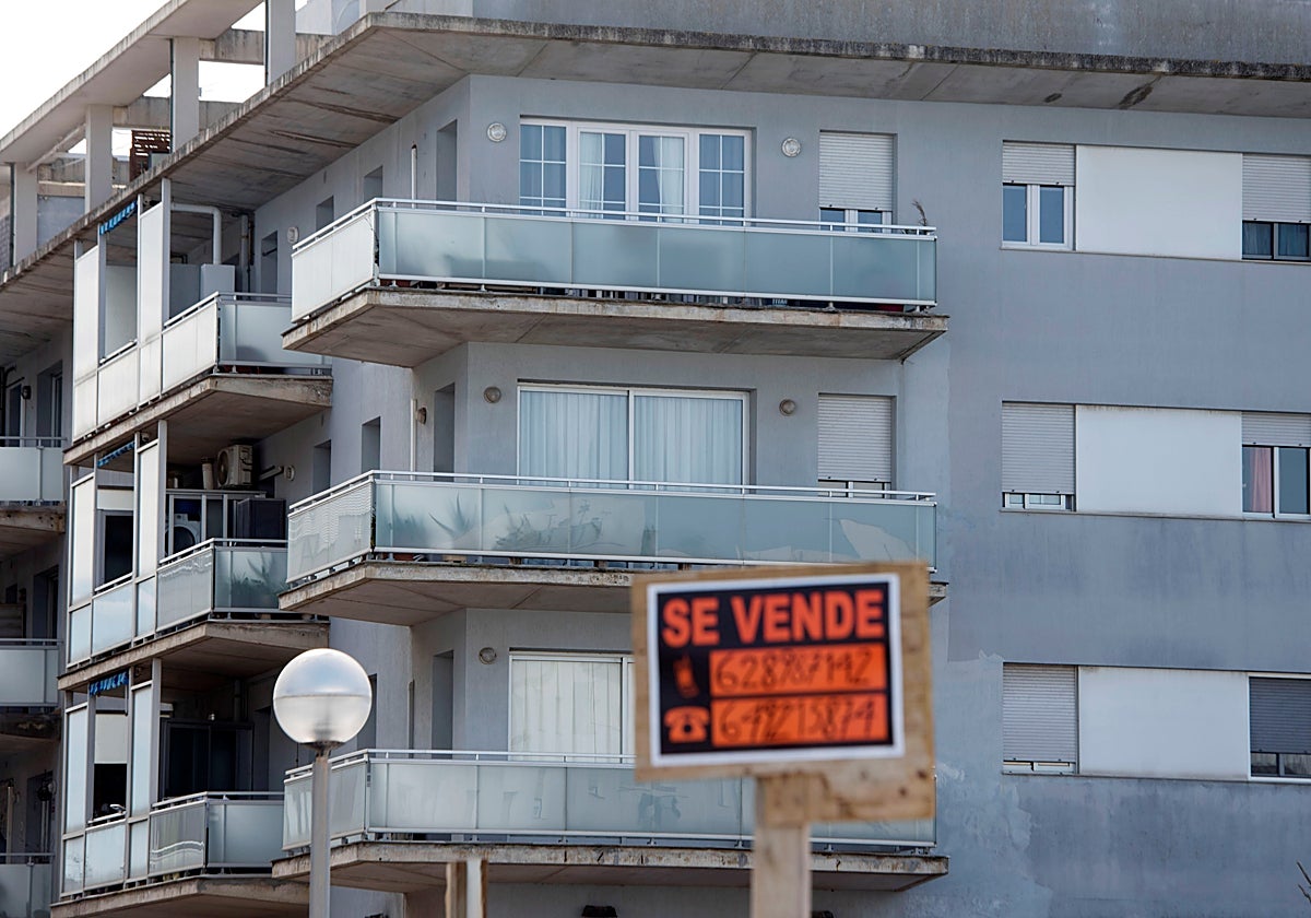 Bloque de pisos junto a cartel de 'se vende'