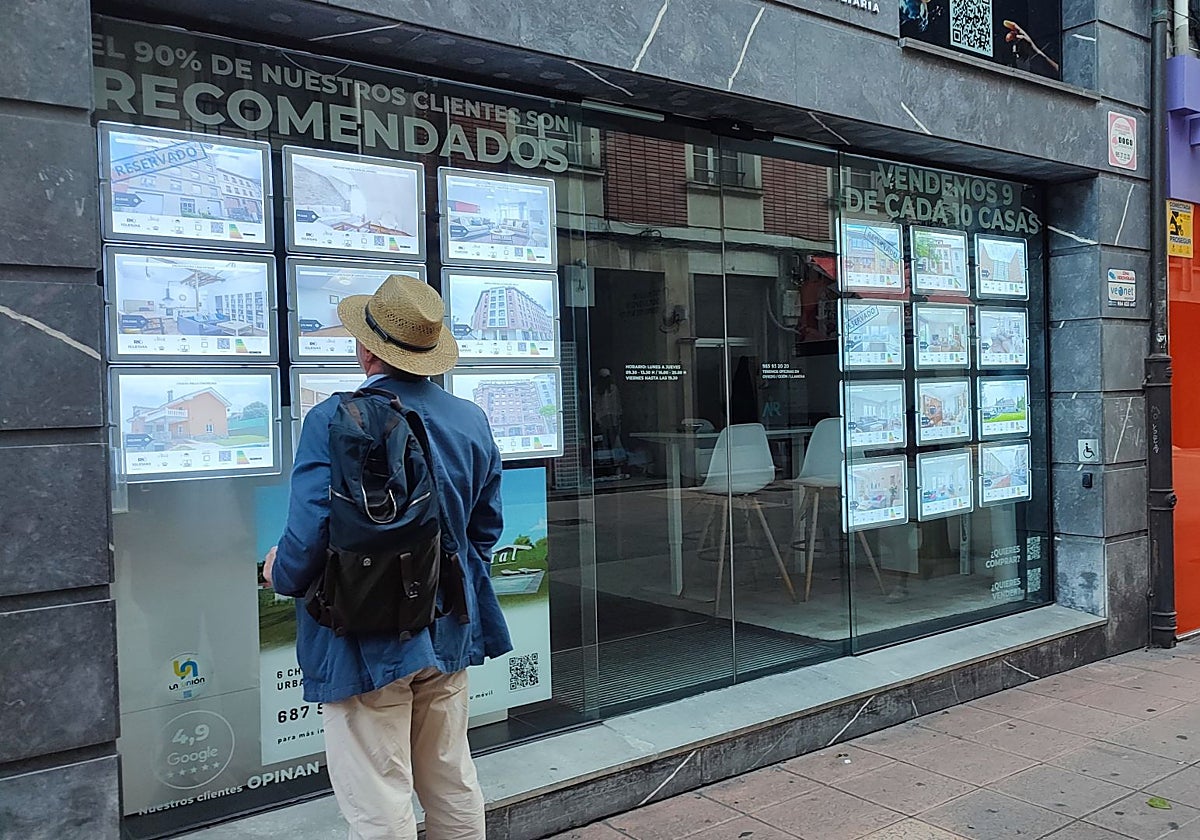 Un hombre delante de una agencia inmobiliaria en Oviedo