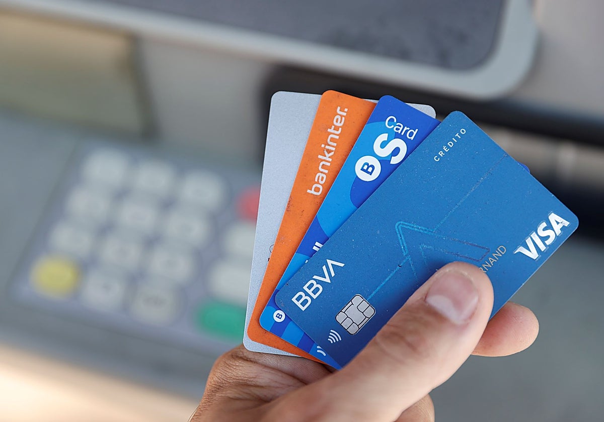 Un usuario con varias tarjetas bancarias frente a un cajero