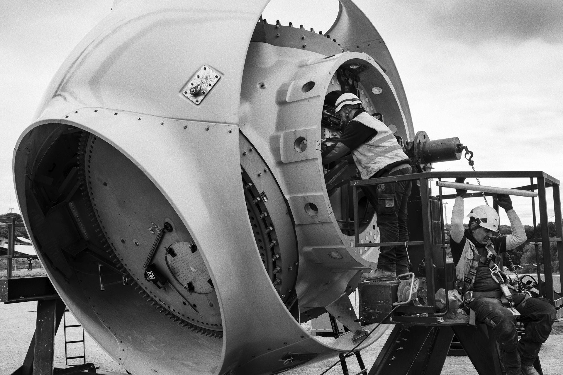 Enero de 2024, Parque Eólico de Muniesa (Teruel). Arriba, Un operario dirige un aspa de un aerogenerador durante el proceso de montaje. Abajo, operarios trabajan en el interior del rotor de uno de los aerogeneradores.