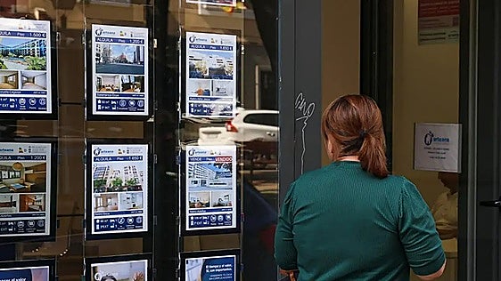 Una mujer frente al escaparate de una agencia inmobiliaria.
