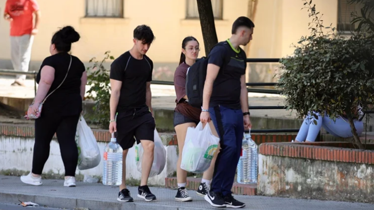 Dos jóvenes acarrean garrafas de agua