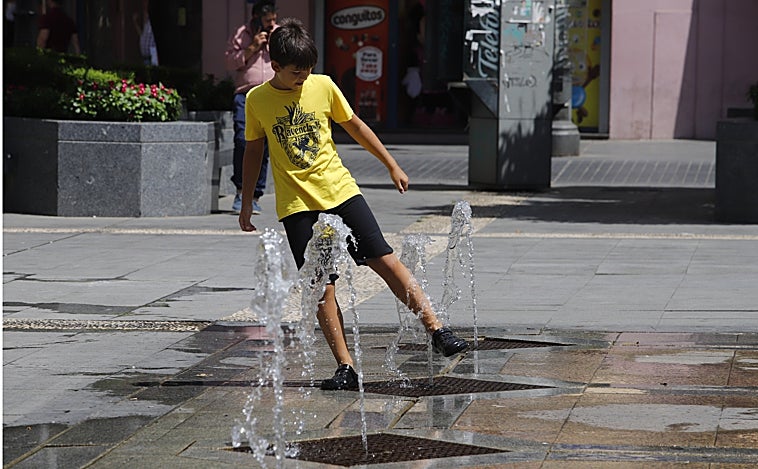 Un joven juega con la fuente de la plaza de las Tendillas de Córdoba