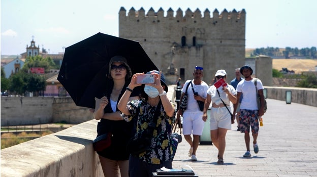 Turistas bajo un paraguas en el Puente Romano de Córdoba